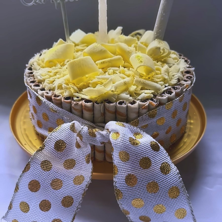 Torta de cumpleaños con virutas de chocolate blanco y moño de lunares dorados