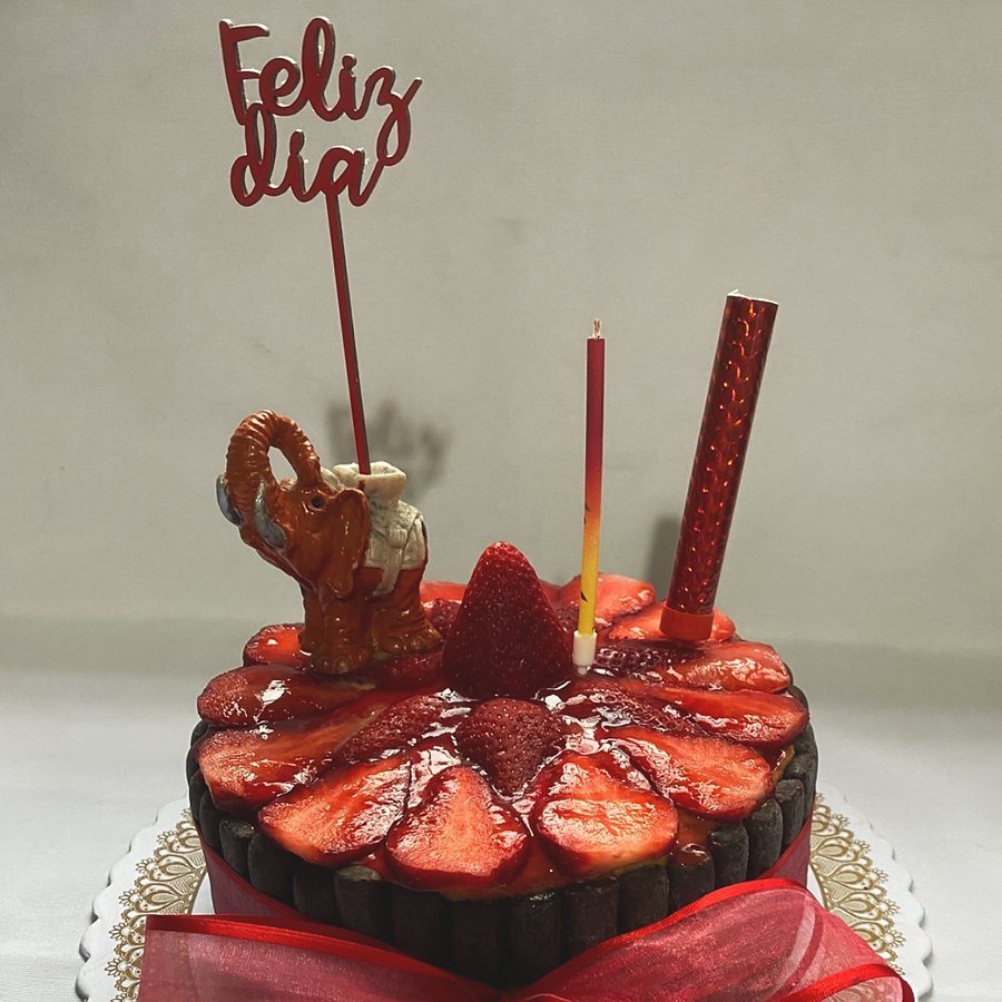 Torta de cumpleaños de chocolate con frutillas frescas y moño rojo