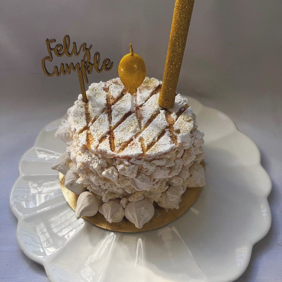 Torta de cumpleaños de merengue con hilos de caramelo y velita dorada